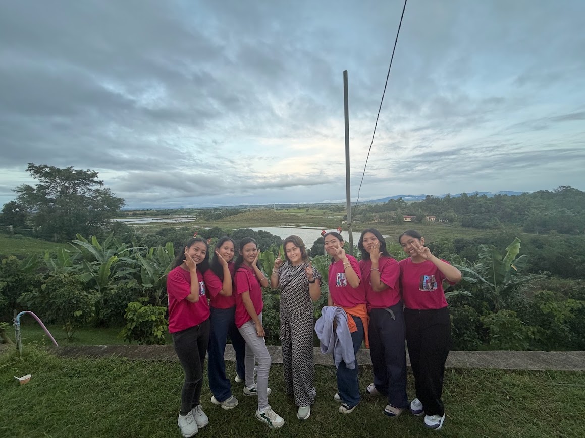Youth in Open Heaven shirts with a team member above the rice fields and river.