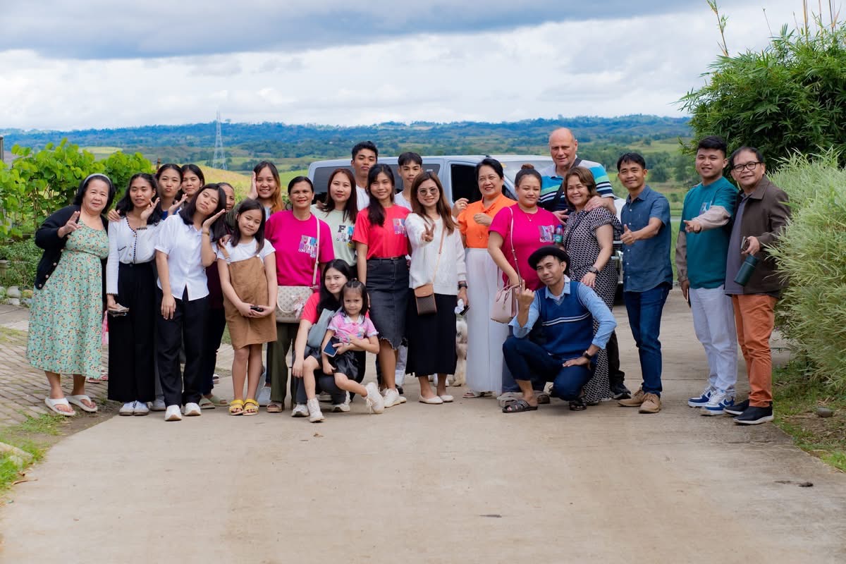 The team on a country road, rolling hills behind, the van at the back.