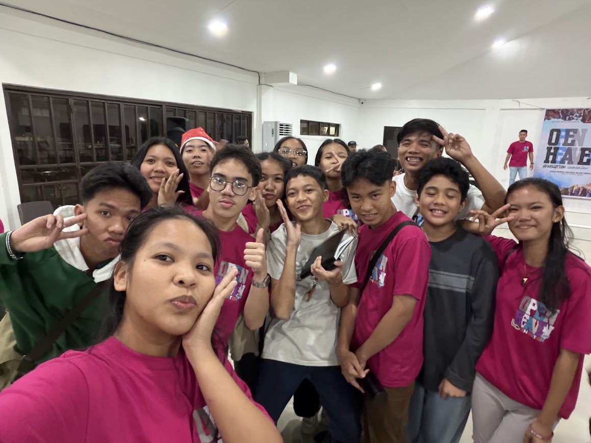 Youth volunteers crowd in for a selfie, peace signs up.