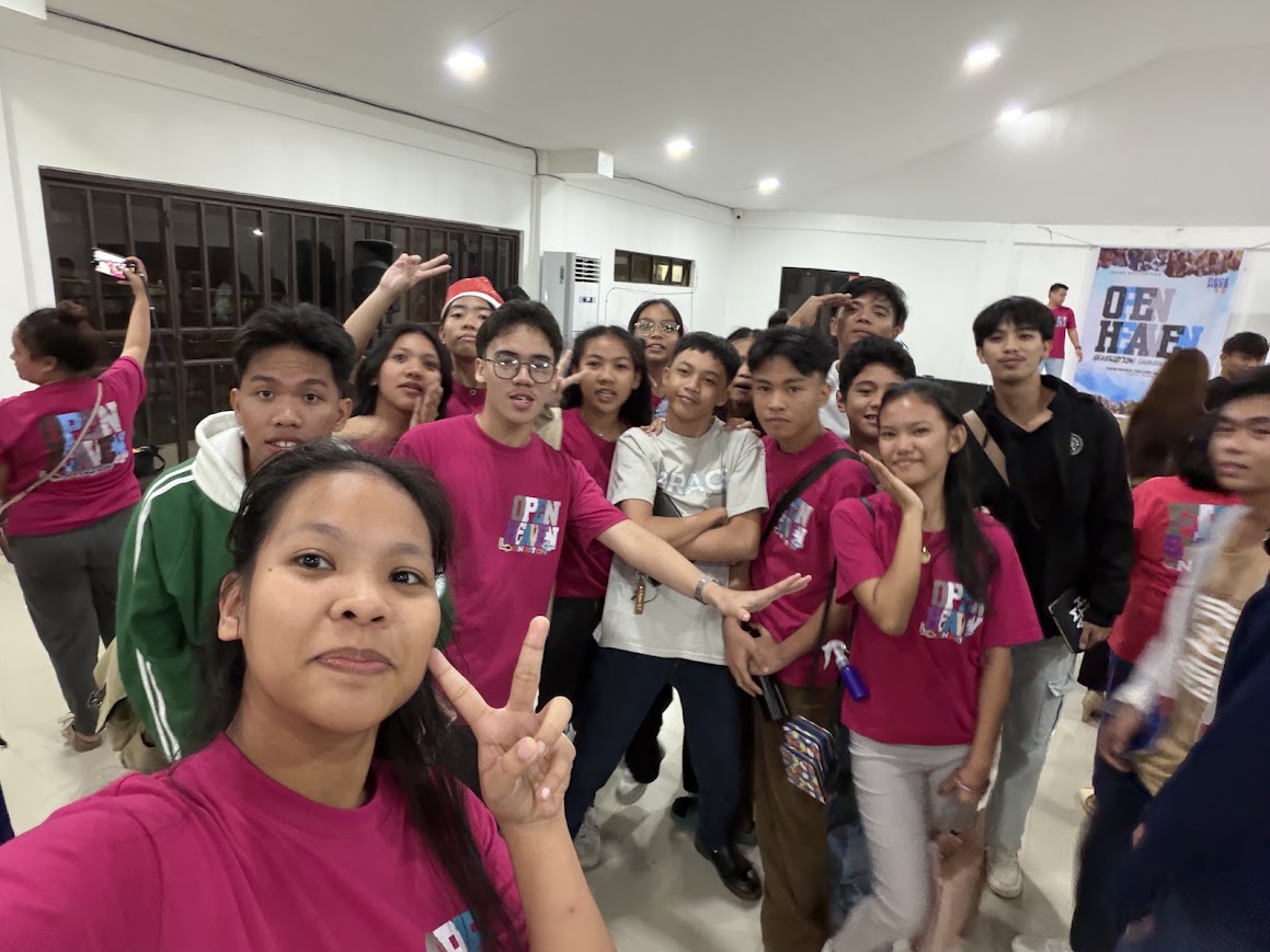 Youth selfie in front of the Open Heaven banner.