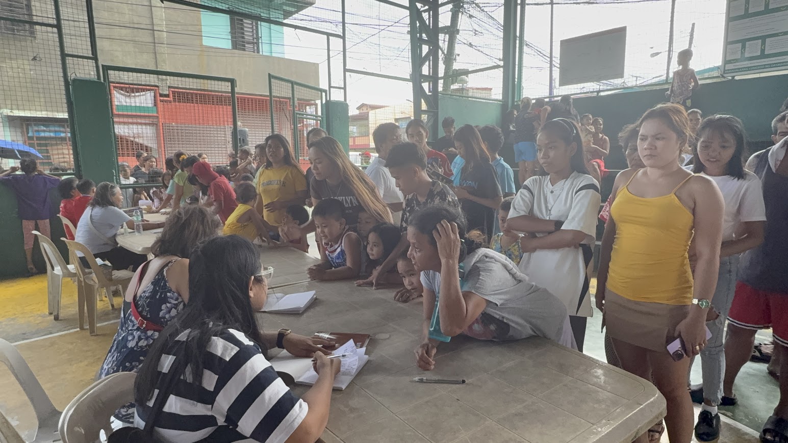 Mothers and children crowd the sign-in book as the list grows.
