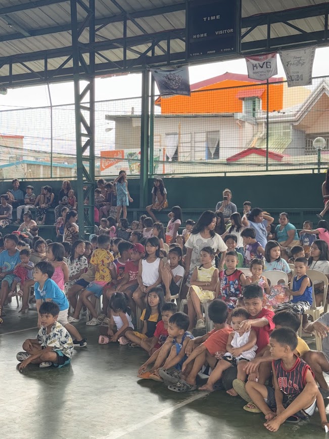 Children seated in rows, the stands filling behind them.