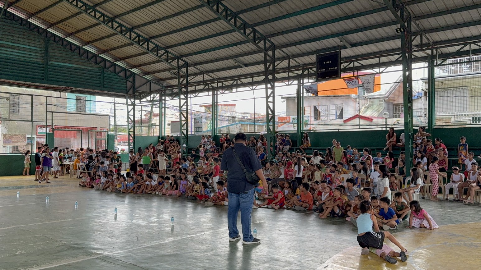 Children cluster close as a team member speaks into the mic.