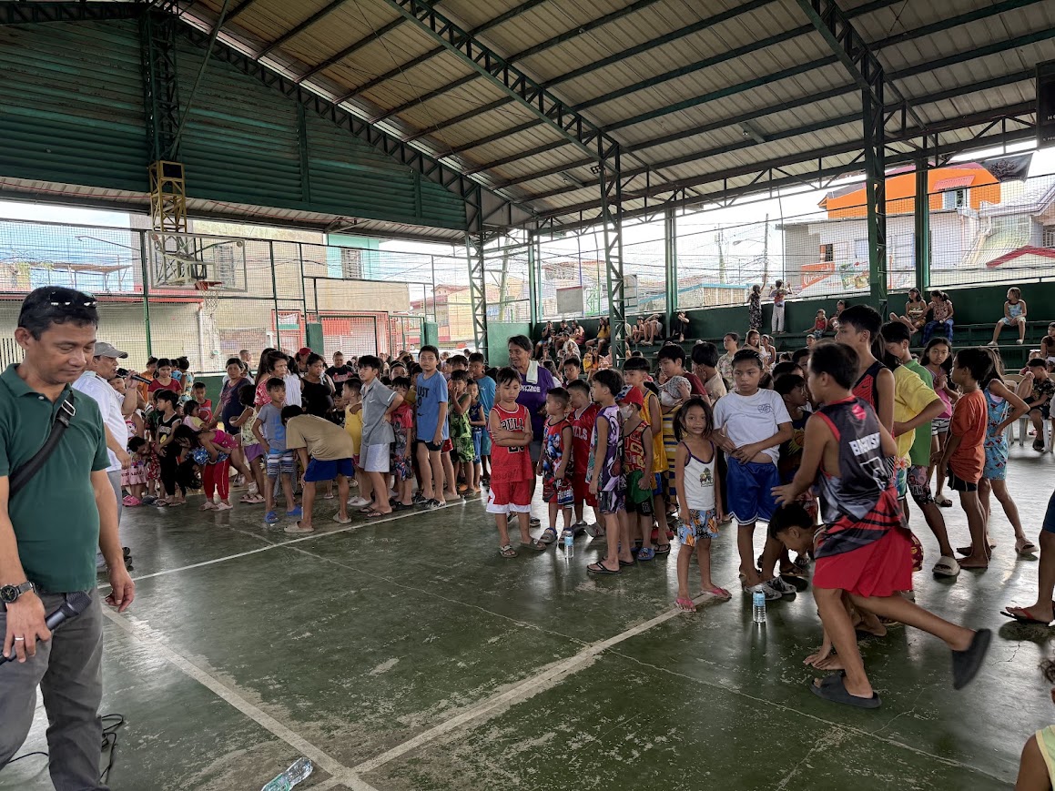 A leader at the mic brings the children together for the start of the program.