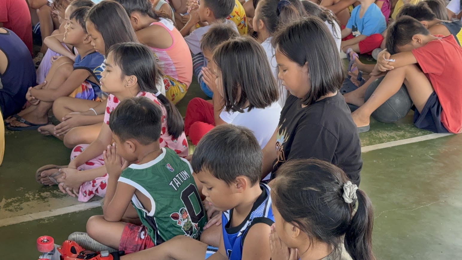 Children at the front of the court during a time of prayer.