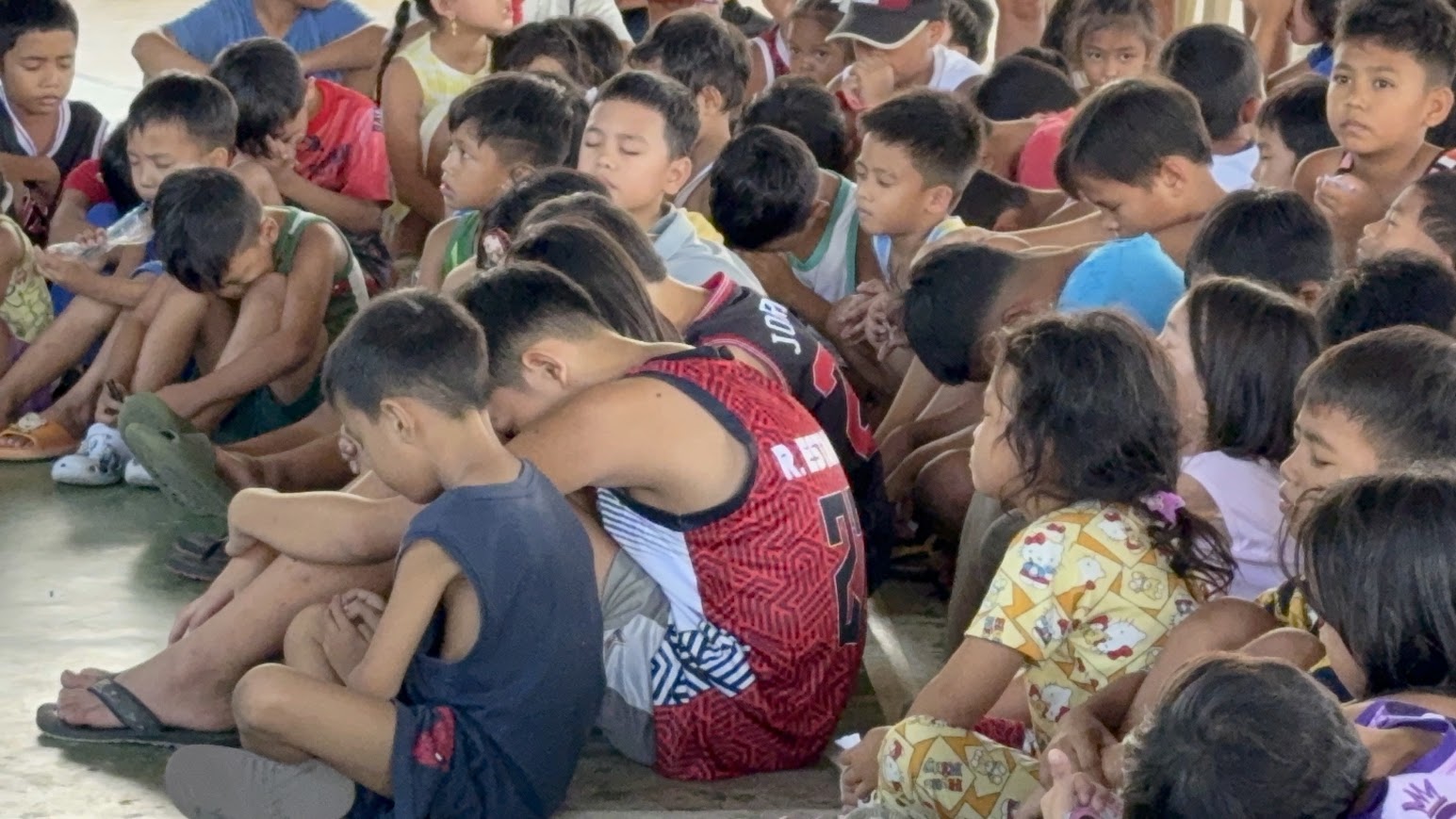 Children in prayer in the front rows.