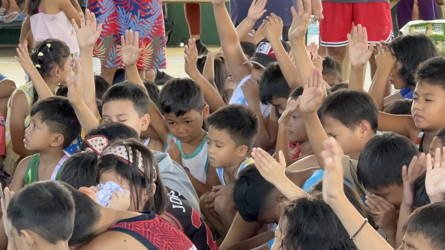 Hands lifted across the crowd; a young girl wipes her eyes.