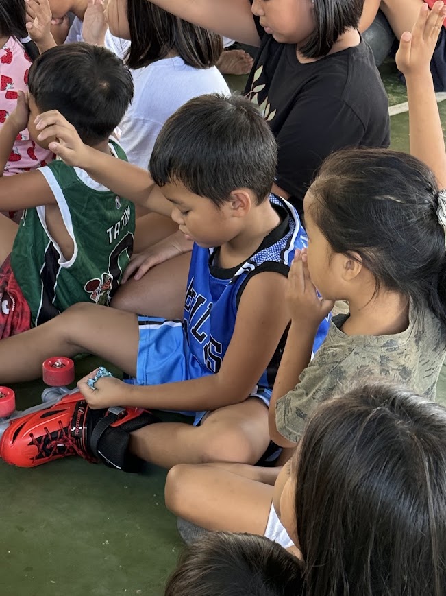A boy still wearing his roller skates, hand to his head in prayer.