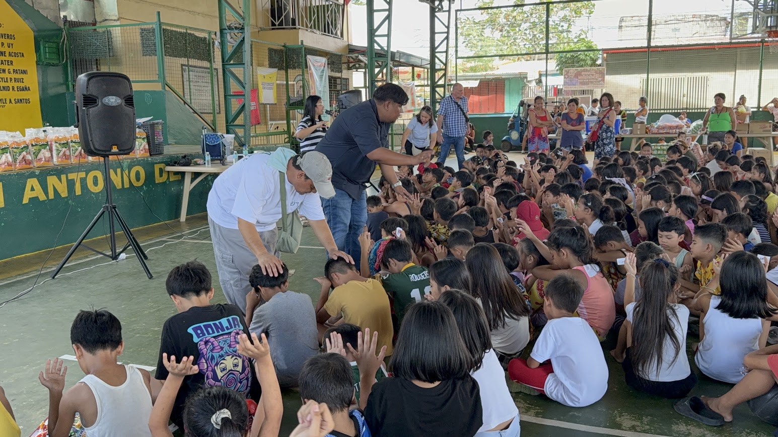 Two team members lay hands on children at the front of the court.