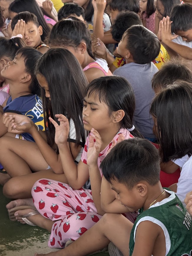 A group of children with hands lifted together.