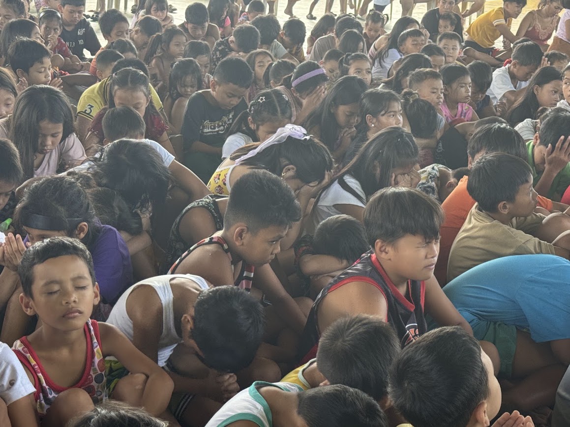 Hundreds of children with heads bowed across the court.
