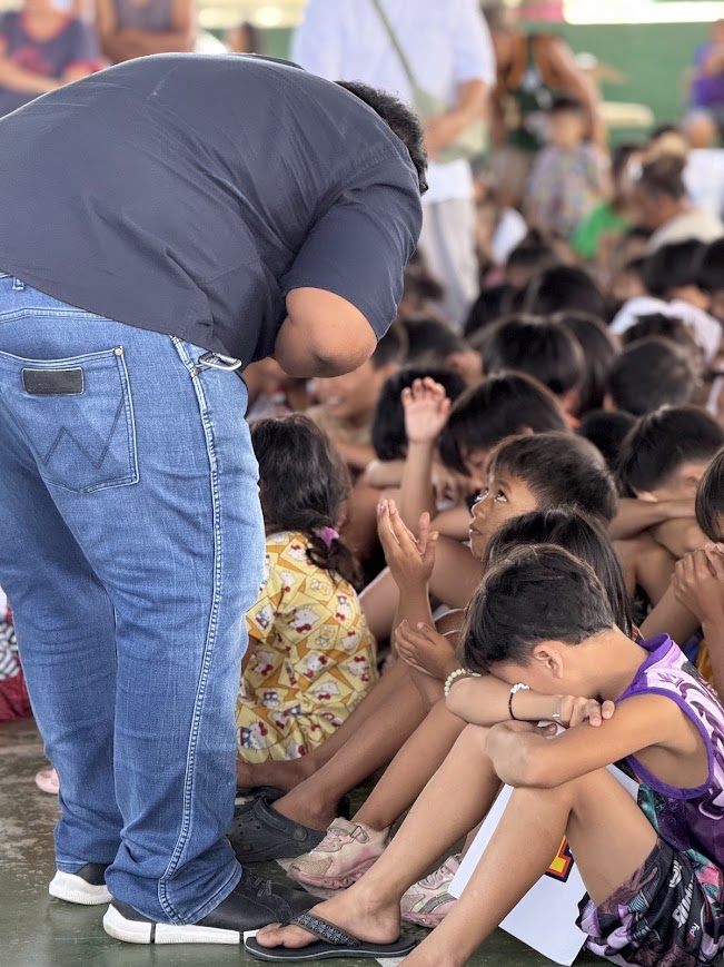 A team member bends down to pray with the children.