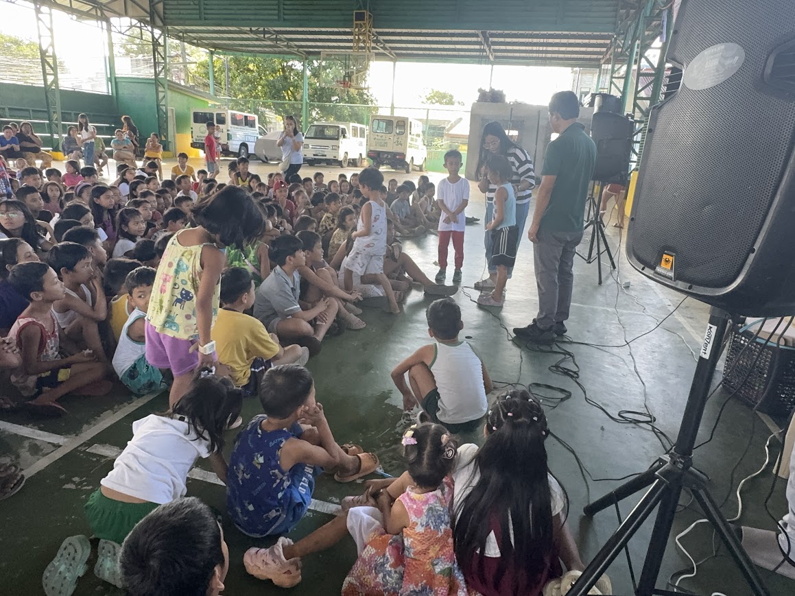 Two children are brought to the front as a team member speaks.