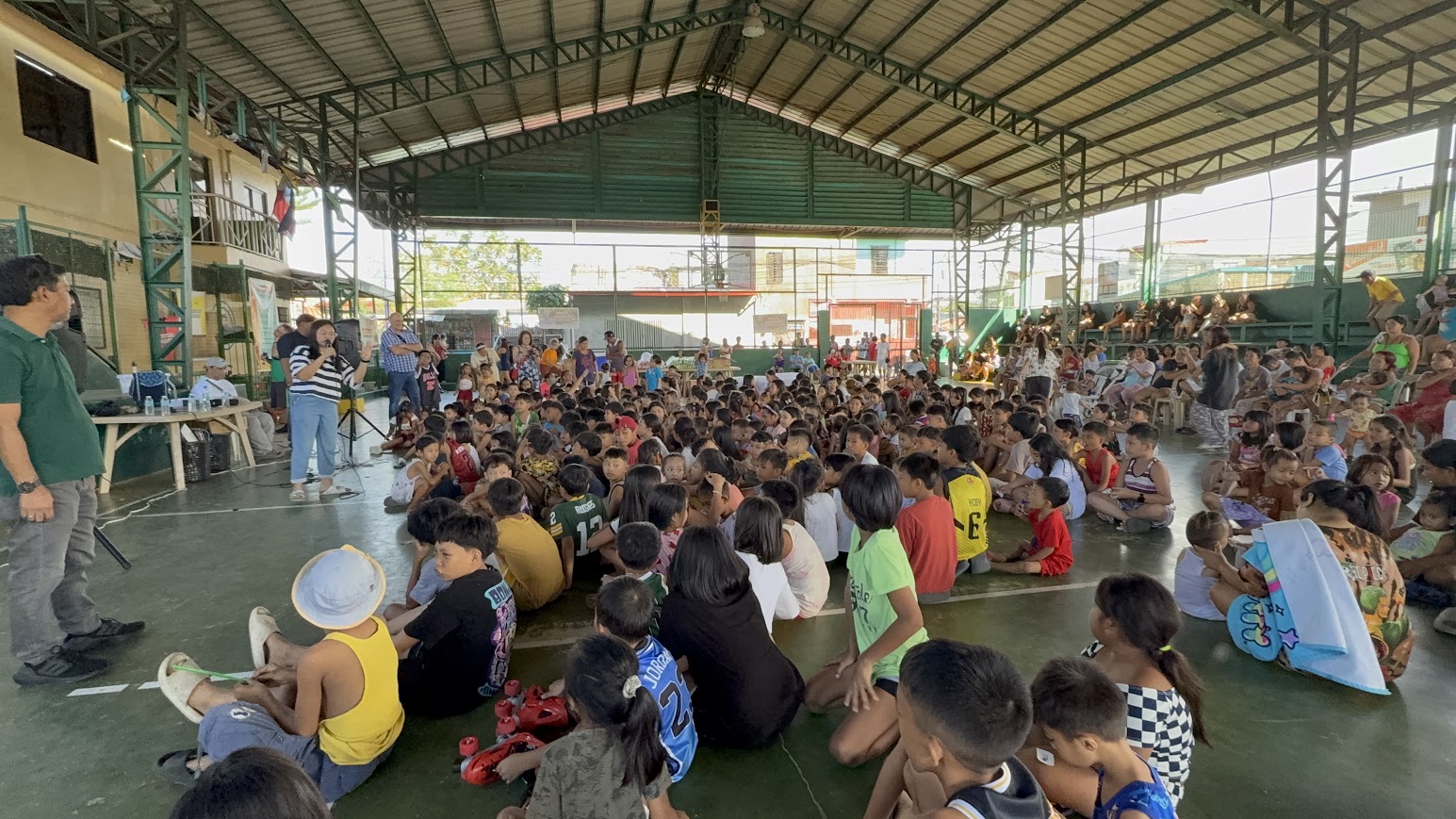 From the front — the leader at the mic, the full court seated and listening.