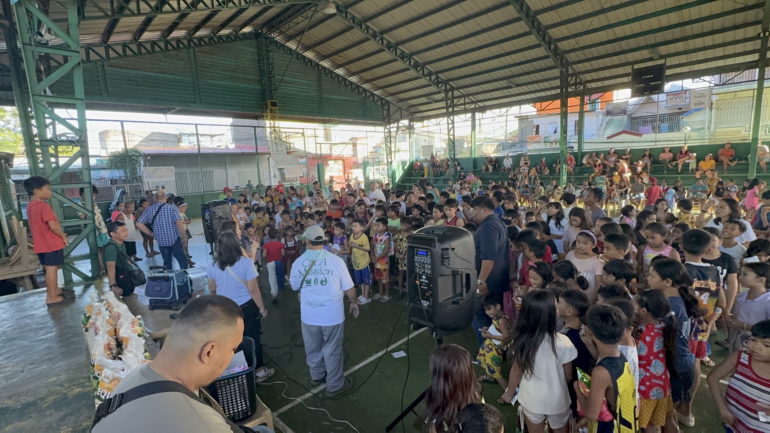 Gift bags staged at the side as the team addresses the packed court.